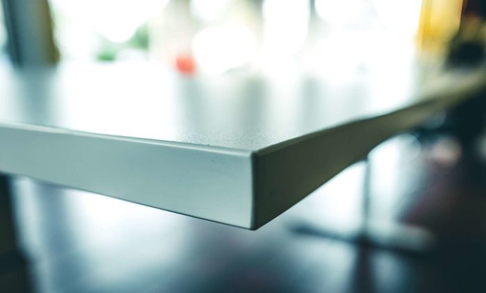 Nahaufnahme der Tischkante mit feuchtigkeitsabweisender und langlebiger Oberfläche in robuster Officequalität.
